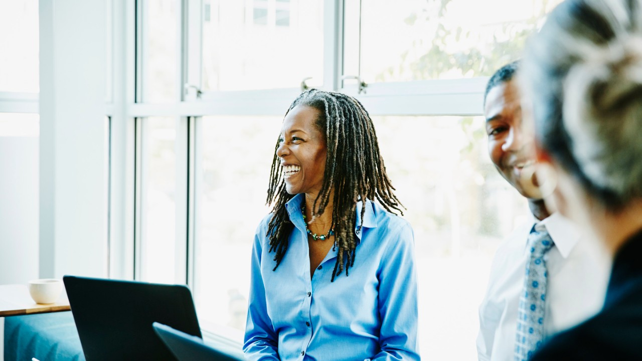 Laughing businesswoman in team meeting in office conference room