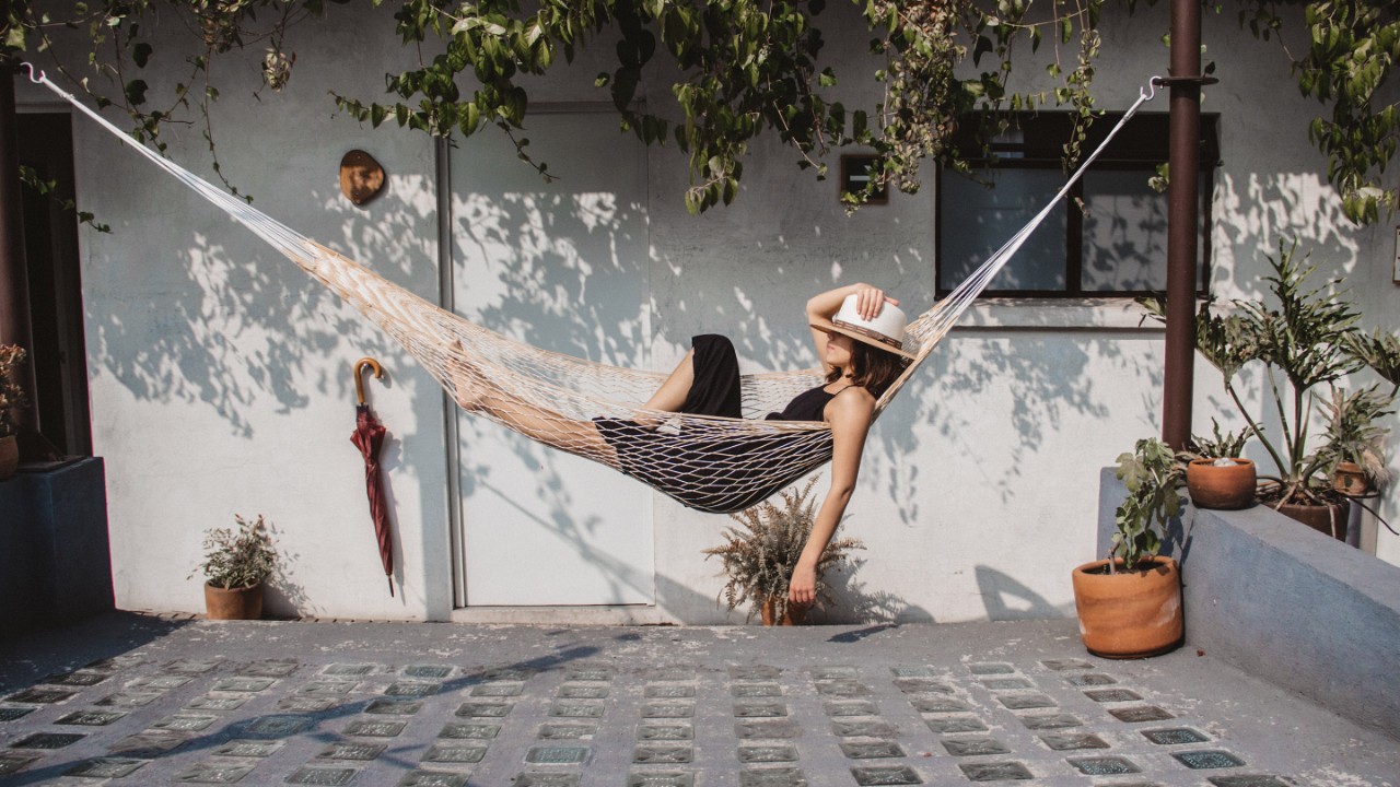 Woman Relaxing In Hammock Against Wall At Yard