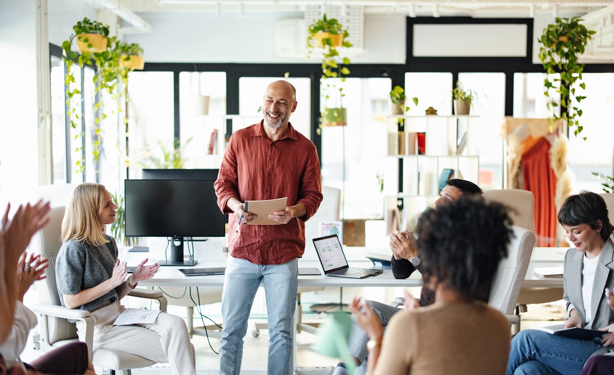 A group of coworkers engages in a collaborative session, focusing on teamwork and communication in a modern office setting with natural lighting and green plants.