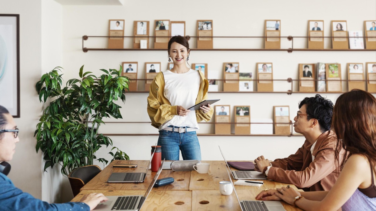 Grupp av unga japanska yrkesverksamma som arbetar på bärbara datorer i ett samarbetsutrymme.