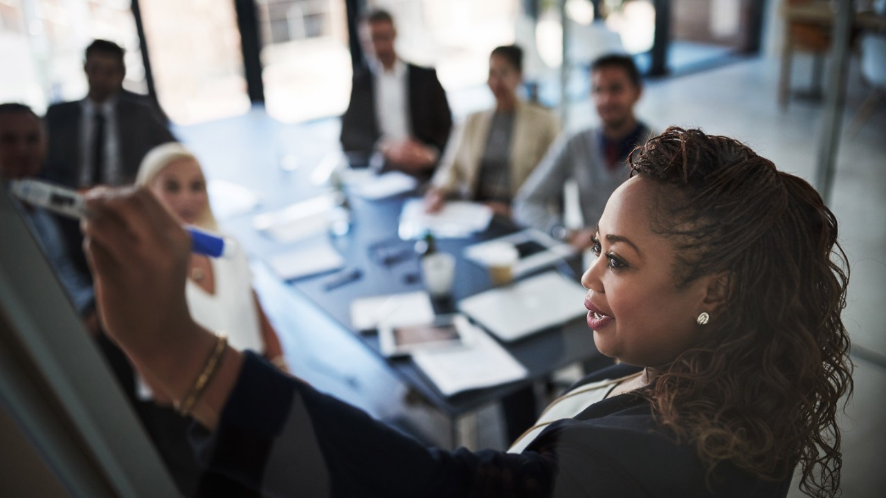 High angle shot of a young businesswoman explaining work related stuff during a presentation to work colleagues in a boardroom