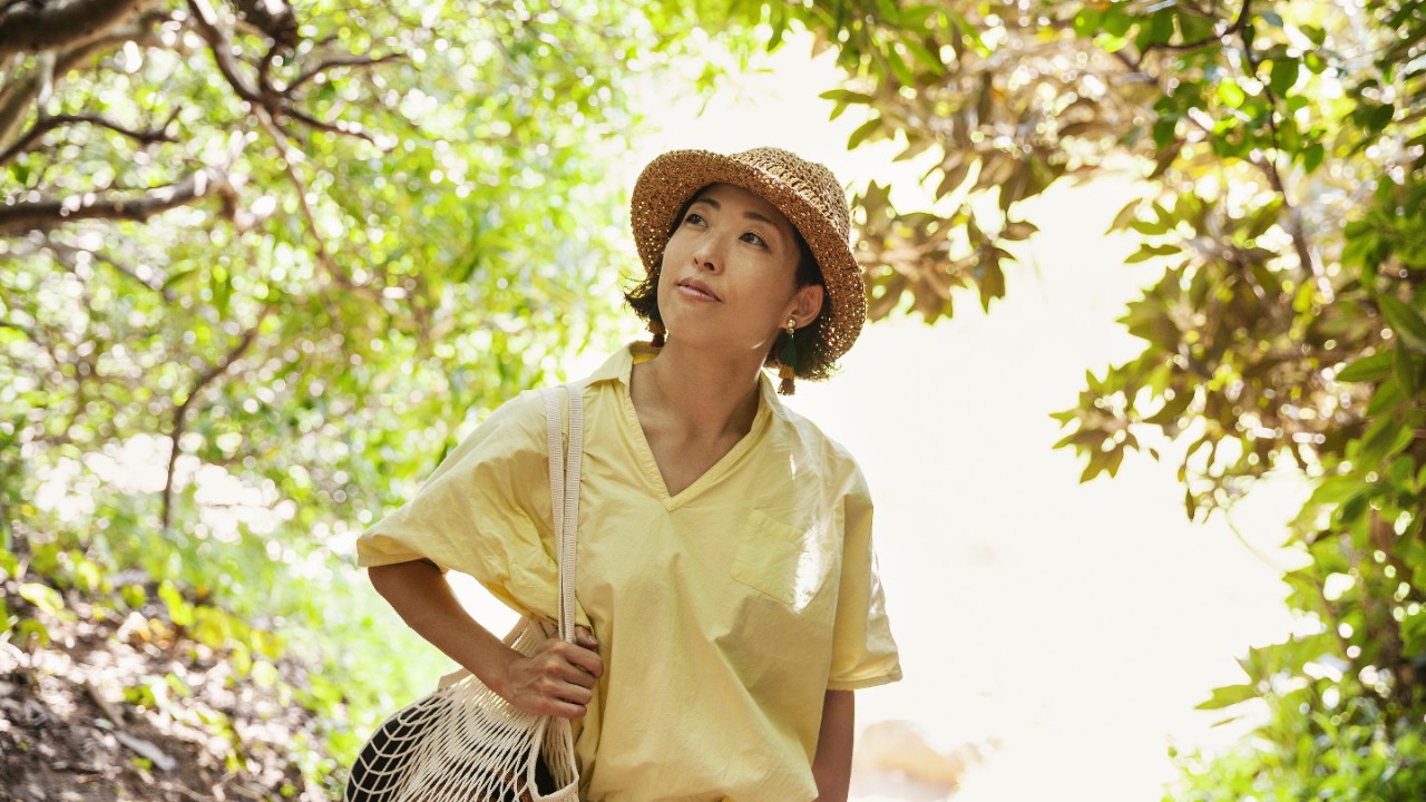 穿著亮黃色襯衫的女士在森林中走路